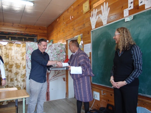 Stewart Duff and Professor Sue Carrington handing over a laptop to a Bhutanese teacher